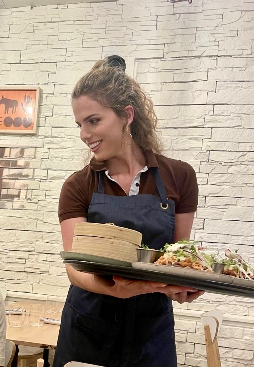 Mona, carrying a tray of dishes